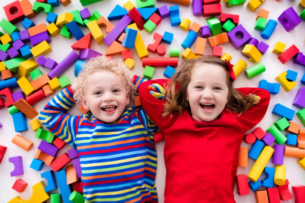 Fröhliche Kinder Mitten in buntem Spielzeug.